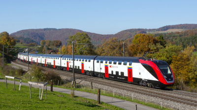 A Swiss Federal Railways (SBB) double- decker train traveling through a scenic landscape, showcasing modern rail technology, digitalization, and predictive maintenance solutions