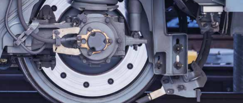 Close-up of a railway axlebox and suspension system, showcasing intricate mechanical components used for predictive maintenance and digital tracking
