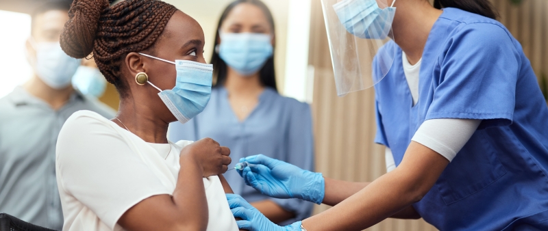 girl taking a vaccine and surrounded by nurses